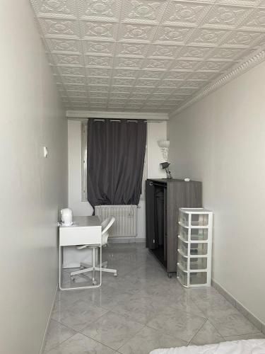 Cette chambre comprend un bureau, une table et une fenêtre. dans l'établissement Colocation maison - Villeurbanne près de Lyon, à Villeurbanne