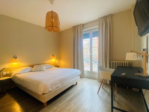 a bedroom with a bed and a desk and a window at Logis Hôtel Marguerite in Orléans