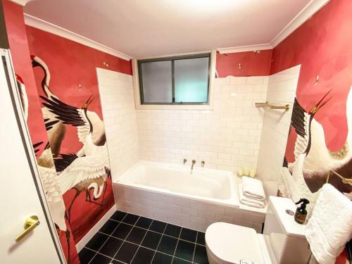 a bathroom with a white tub and a red wall at Darling Harbour stunning city location with pool, gym, wifi, Netflix in Sydney