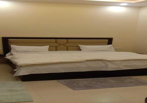 Mayur Palace By WB Inn في آغْرا: غرفة نوم بسرير كبير عليها شراشف ووسائد بيضاء