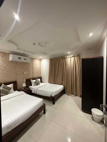 a hotel room with two beds and a window at شقق الجناح الأبيض للشقق المخدومة in Dammam