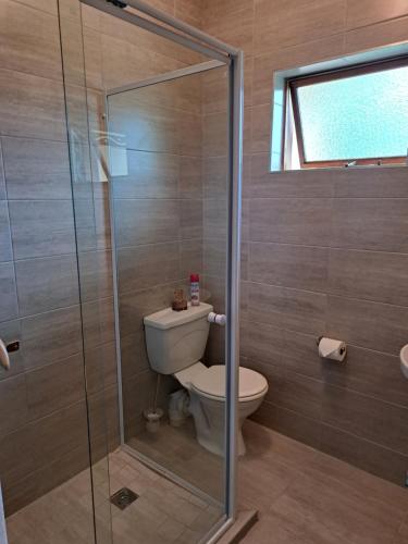a bathroom with a toilet and a glass shower at Candleberry Stay in East London