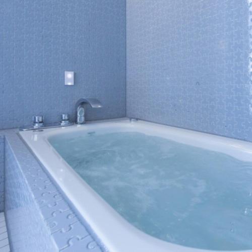 a bath tub with a faucet in a bathroom at Namari Onsen Kokoro No Toki Jusangatsu in Hanamaki