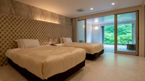 a hotel room with two beds and a window at Namari Onsen Kokoro No Toki Jusangatsu in Hanamaki