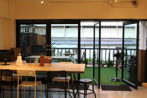 バンコクにあるジャム ホステル バンコクの大きな窓のある客室で、テーブルと椅子が備わります。