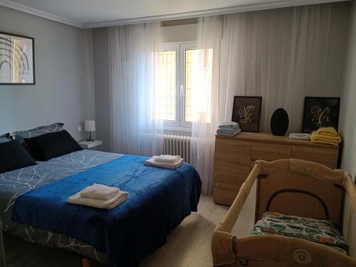 a bedroom with a bed and a chair and a window at Bonito piso Villafria in Oviedo