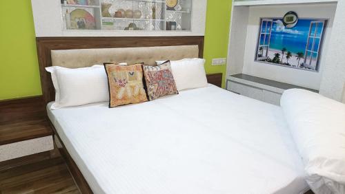 um quarto com uma cama com lençóis brancos e almofadas em Gokul Niwas Home Stay em Udaipur