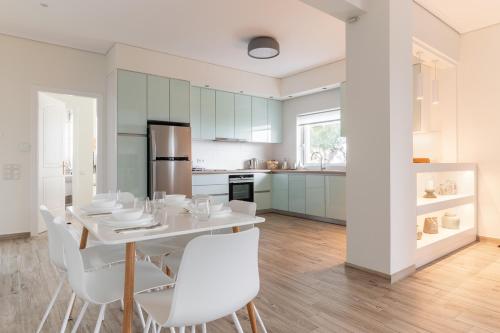 een keuken en eetkamer met een witte tafel en stoelen bij Villa Katrin in Pylos