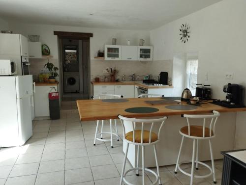 a kitchen with a wooden counter and two bar stools at Charmante longère près des côtes Finistériennes in Plouégat-Guérand