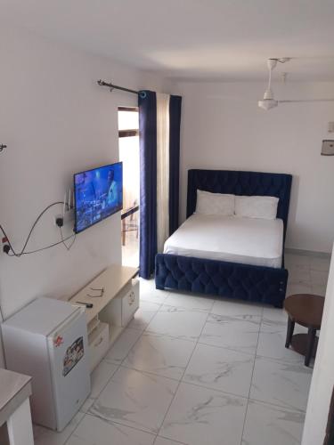 a bedroom with a bed and a tv on a wall at Amber Apartment in Mombasa
