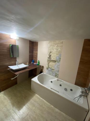een badkamer met een bad, een bureau en een wastafel bij Woods Prashanti Homestay A in Alibaug