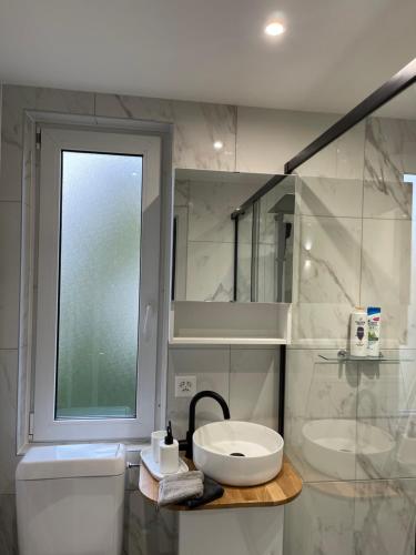 a bathroom with a sink and a toilet and a window at Appartement Wonder 2 au centre de Couvet in Couvet