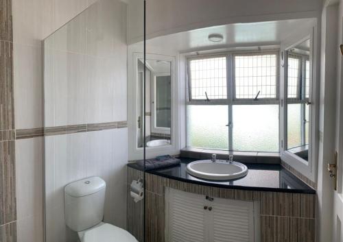 a bathroom with a toilet and a sink and a window at 43 Montego Bay, Caribbean Estate in Port Edward