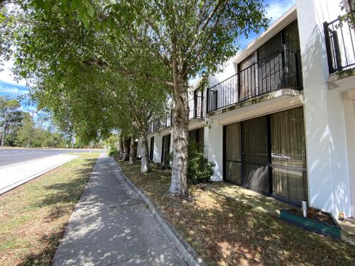 a building with trees next to a street at Connells Motel & Serviced Apartments in Traralgon