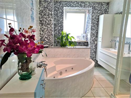 a bathroom with a pink tub and flowers in a vase at Apartamento Albertina in Kleinheubach