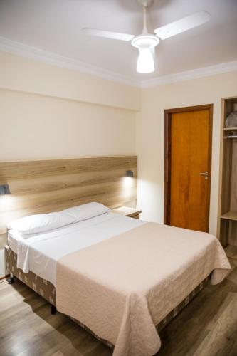 a bedroom with a large white bed with a wooden headboard at Lisboa Hotel in Poços de Caldas