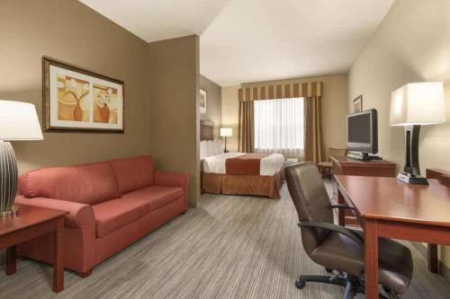a hotel room with a couch and a desk and a bed at Seffner Inn and Suites in Seffner