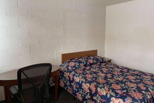 a small bedroom with a bed and a chair at Travelodge by Wyndham Rockford South in Rockford