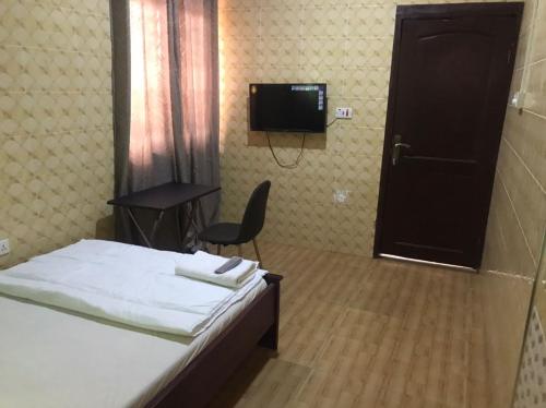 - une chambre avec un lit, une chaise et une télévision dans l'établissement Temaya Cottage Lodge, à Tamale