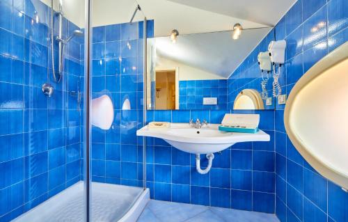 y baño de azulejos azules con lavabo y ducha. en Residenza D'epoca La Corallina, en Castellabate