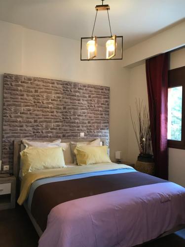 1 dormitorio con 1 cama grande y pared de ladrillo en Villa Under Meteora, en Kalambaka