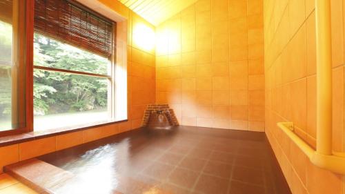 a bathroom with a bath tub and a window at Fujisan Ryokan in Hanamaki