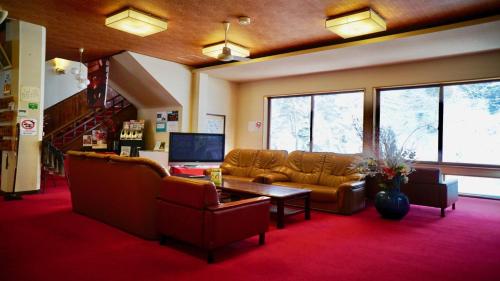 a waiting room with couches and a table and windows at Fujisan Ryokan in Hanamaki