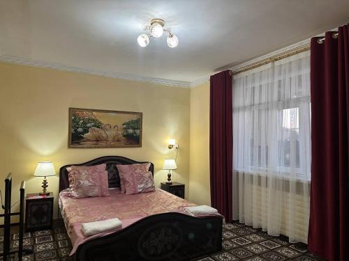 a bedroom with a bed and a window with red curtains at Guest house "NIKA", Nukus in Nukus