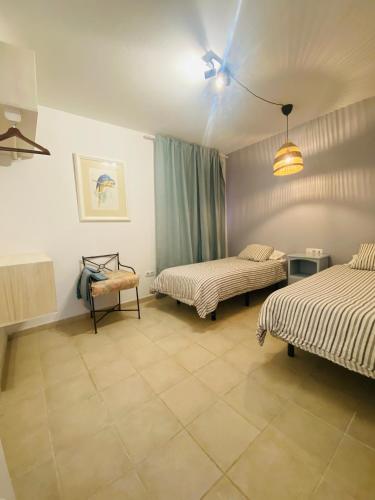 a room with two beds and a chair in it at Sun&Beach 5 in Caleta De Fuste