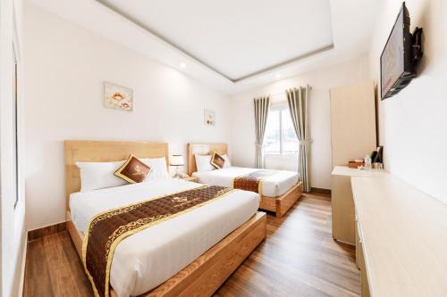 a hotel room with two beds and a television at Golden Bee Hotel in Da Lat