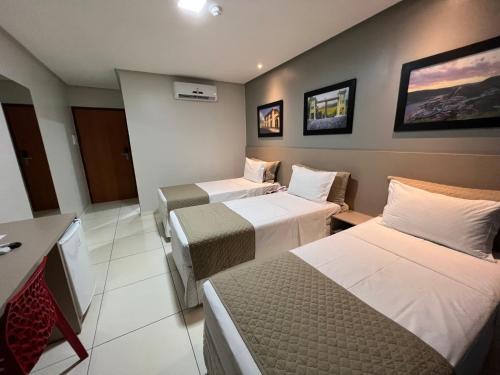 a hotel room with three beds and a tv at Dunen Hotel in Piranhas