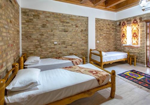 a bedroom with two beds and a brick wall at Dervish Hostel in Bukhara