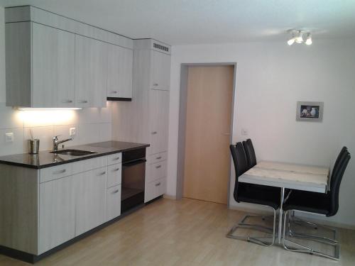 a kitchen with white cabinets and a table and chairs at Hotel Kristall-Saphir Superior in Saas-Almagell
