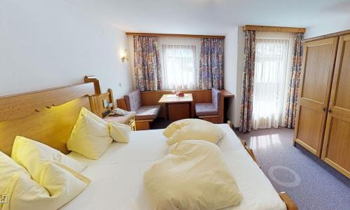 ein Schlafzimmer mit einem großen weißen Bett mit gelben Kissen in der Unterkunft Pension Rosengarten in Tux