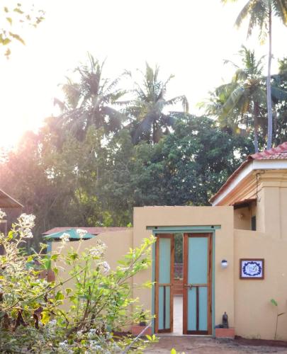 a small house with palm trees in the background at Caju Grove - The Big Yellow Goan House in Guirim