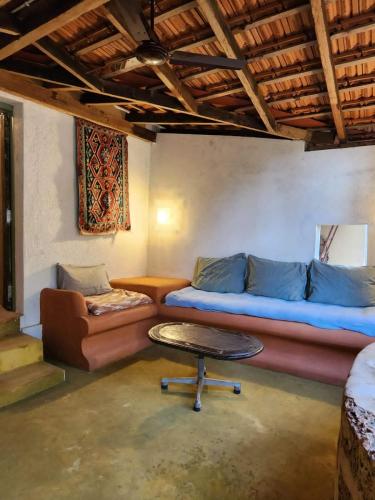 a living room with a couch and a table at Caju Grove - The Big Yellow Goan House in Guirim
