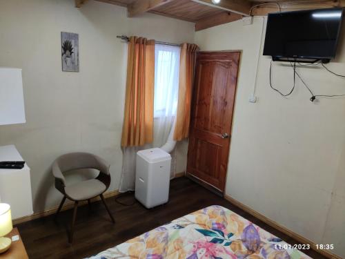 1 dormitorio con 1 cama, 1 silla y TV en Hospedaje Lago Llanquihue, en Llanquihue