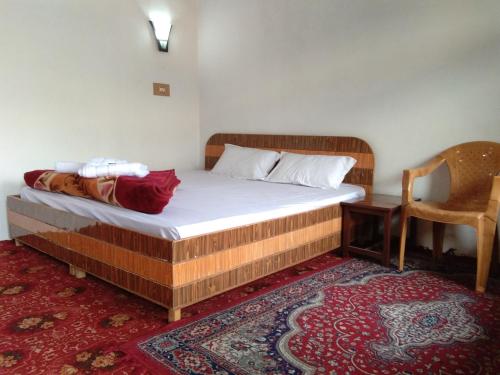 a bedroom with a bed with a chair and a table at Howrah Guest House in Srinagar