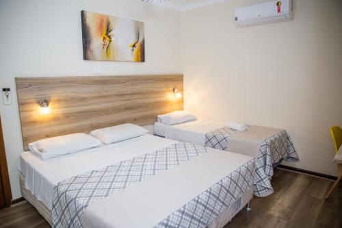 two beds in a hotel room with white sheets at Lisboa Hotel in Poços de Caldas