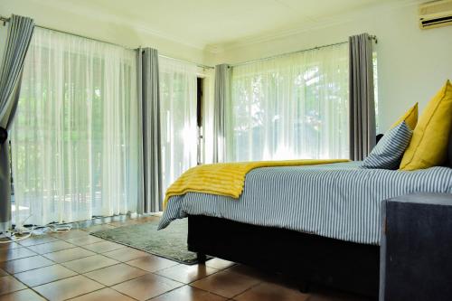 a bedroom with a bed and large glass windows at MTH in Nelspruit