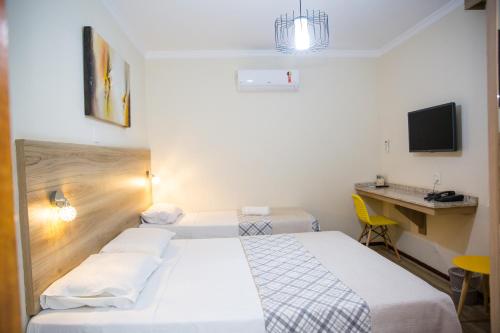 a hotel room with two beds and a desk at Lisboa Hotel in Poços de Caldas