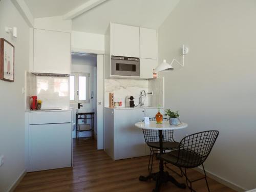 een keuken met witte kasten en een tafel en stoelen bij Maria da Sé Historic House in Porto