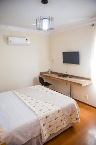 a bedroom with a bed and a desk with a television at Lisboa Hotel in Poços de Caldas