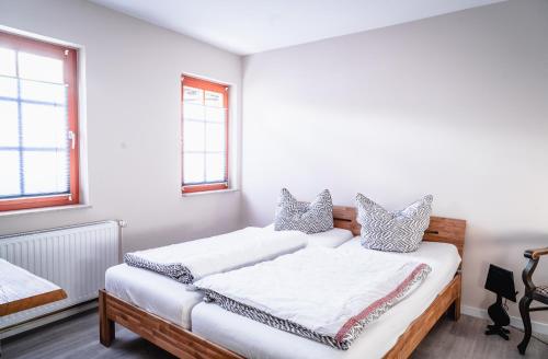 2 camas en una habitación con paredes y ventanas blancas en Apartment am Markt, en Aschersleben