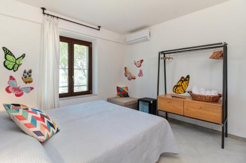 una camera da letto con un letto e uno specchio con farfalle sul muro di Artemisia negli ulivi b&b a Magliano in Toscana