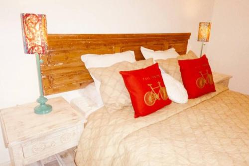 a bed with red and white pillows on it at Departamento con jardin en Green Park, Punta del Este in Punta del Este