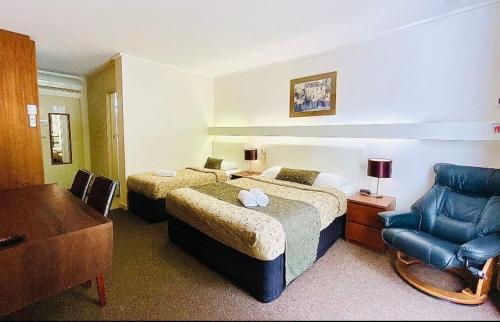 a hotel room with two beds and a chair at Connells Motel & Serviced Apartments in Traralgon