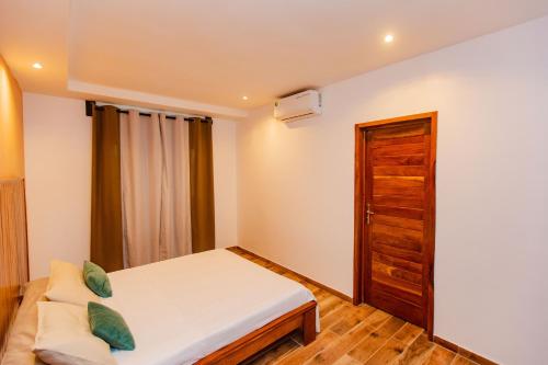 a bedroom with a bed and a wooden door at Résidence Decamaret Warang in Ouoran