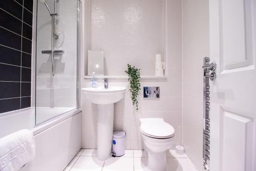 Baño blanco con aseo y lavamanos en 4BR Contractor Town House 2.5bathrooms, 2 free parking spaces managed by Chique Properties, en Milton Keynes