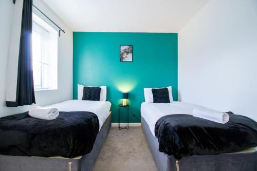 2 camas en una habitación con una pared azul en 4BR Contractor Town House 2.5bathrooms, 2 free parking spaces managed by Chique Properties, en Milton Keynes